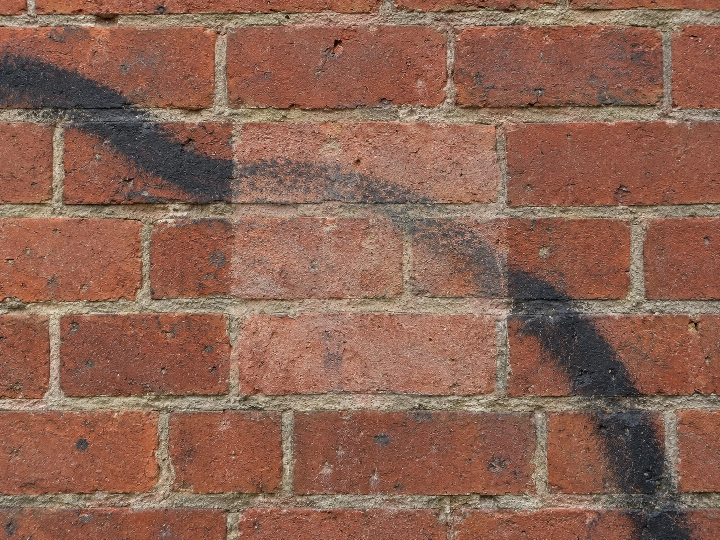 A small cleaning test patch on brick, with faint paint staining still visible.